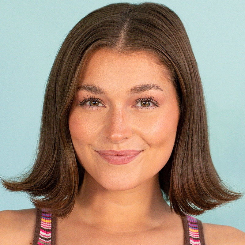 A young woman with straight, shoulder-length brown hair smiles gently. She has light skin, natural makeup, and is wearing a colorful striped tank top. The portrait is in the signature style of Ethan Hardy Benson against a solid light blue background.