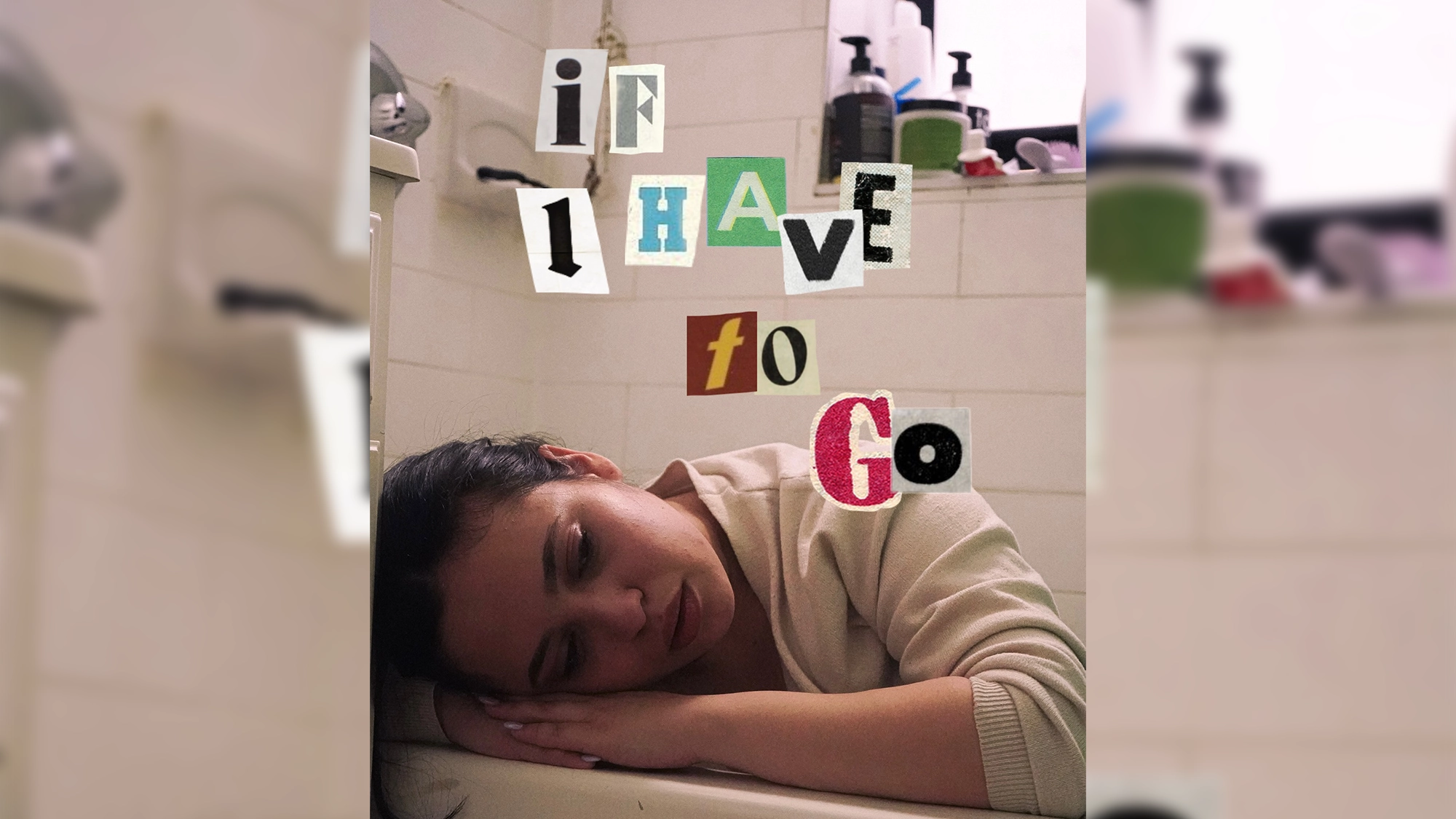 A woman with dark hair rests her head and arms on the edge of a bathtub in a bathroom, looking tired or sad. Above her, cut-out letters spell 