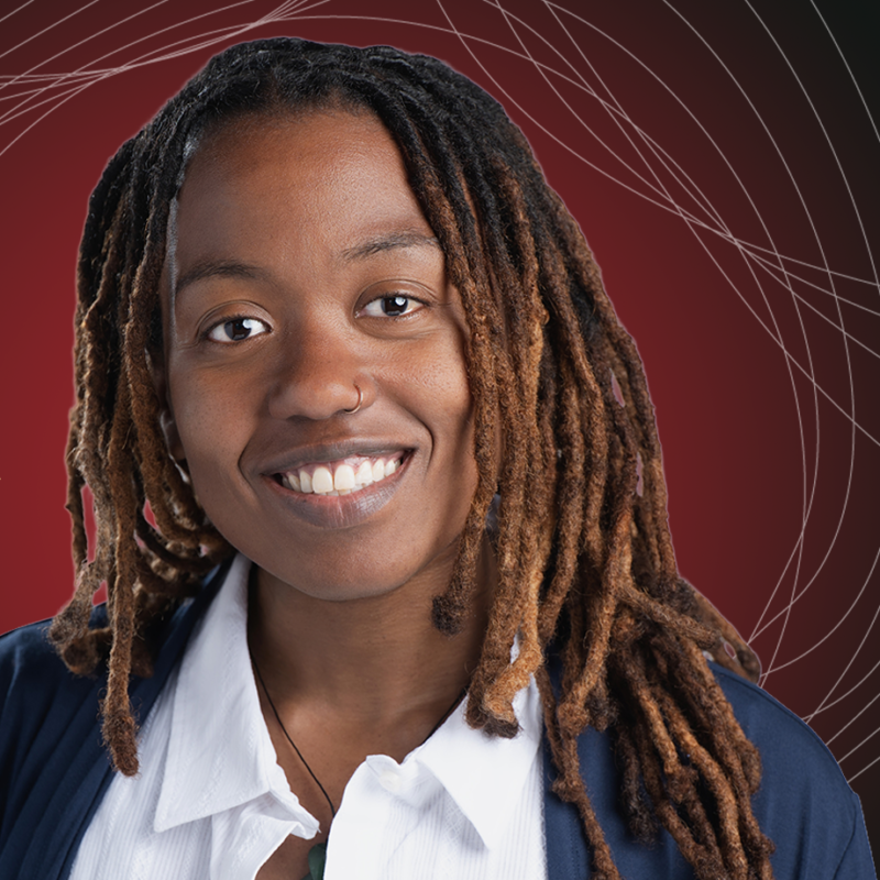 A smiling person with long brown and blonde dreadlocks wears a white collared shirt and dark jacket. The background is deep red with curved, intersecting white lines creating a geometric pattern.