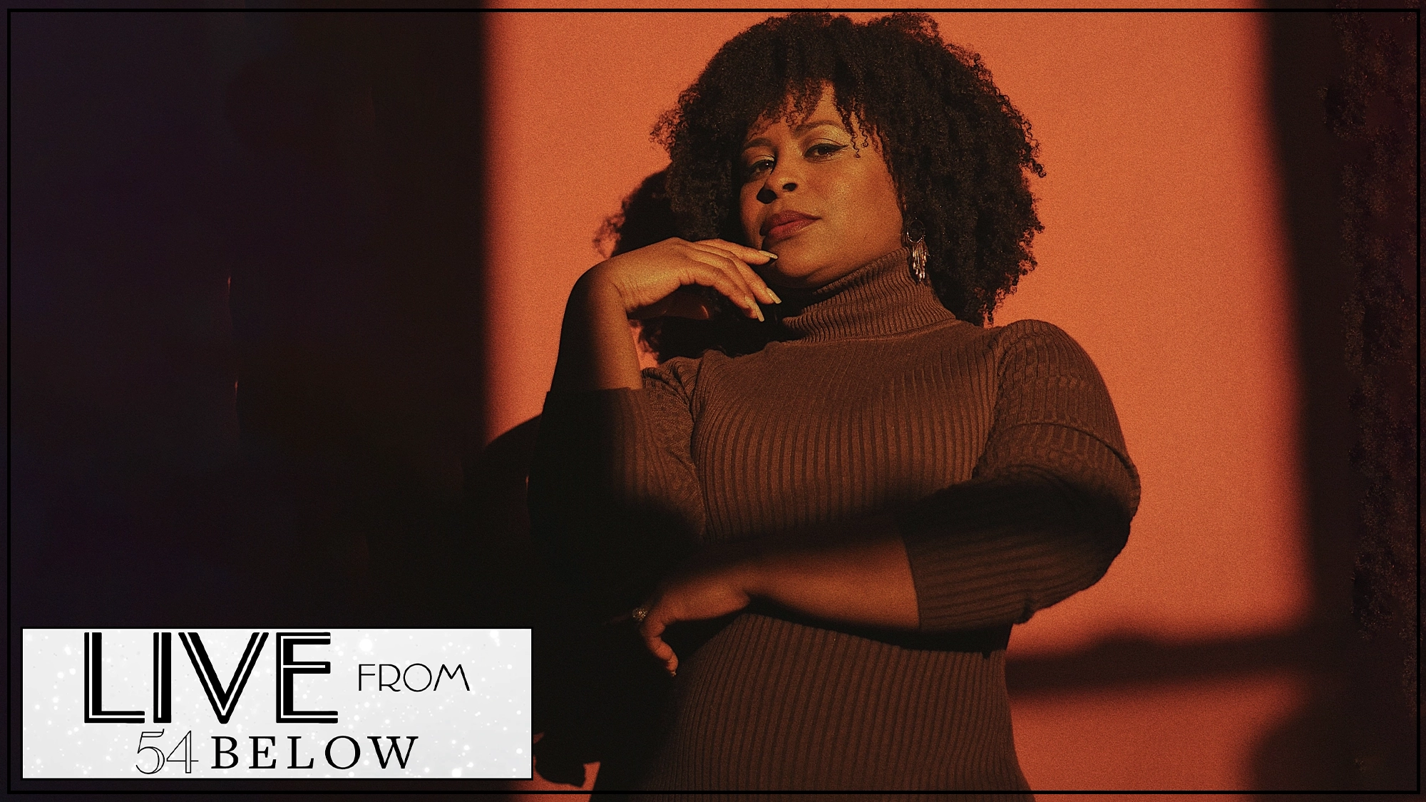 LIVE Alexis Tidwell Bailey A woman with natural curly hair, wearing a ribbed turtleneck sweater, poses with her hand near her face against a warm, orange background. In the bottom left corner, a logo reads “LIVE FROM 54 BELOW,” featuring Alexis Tidwell Bailey.
