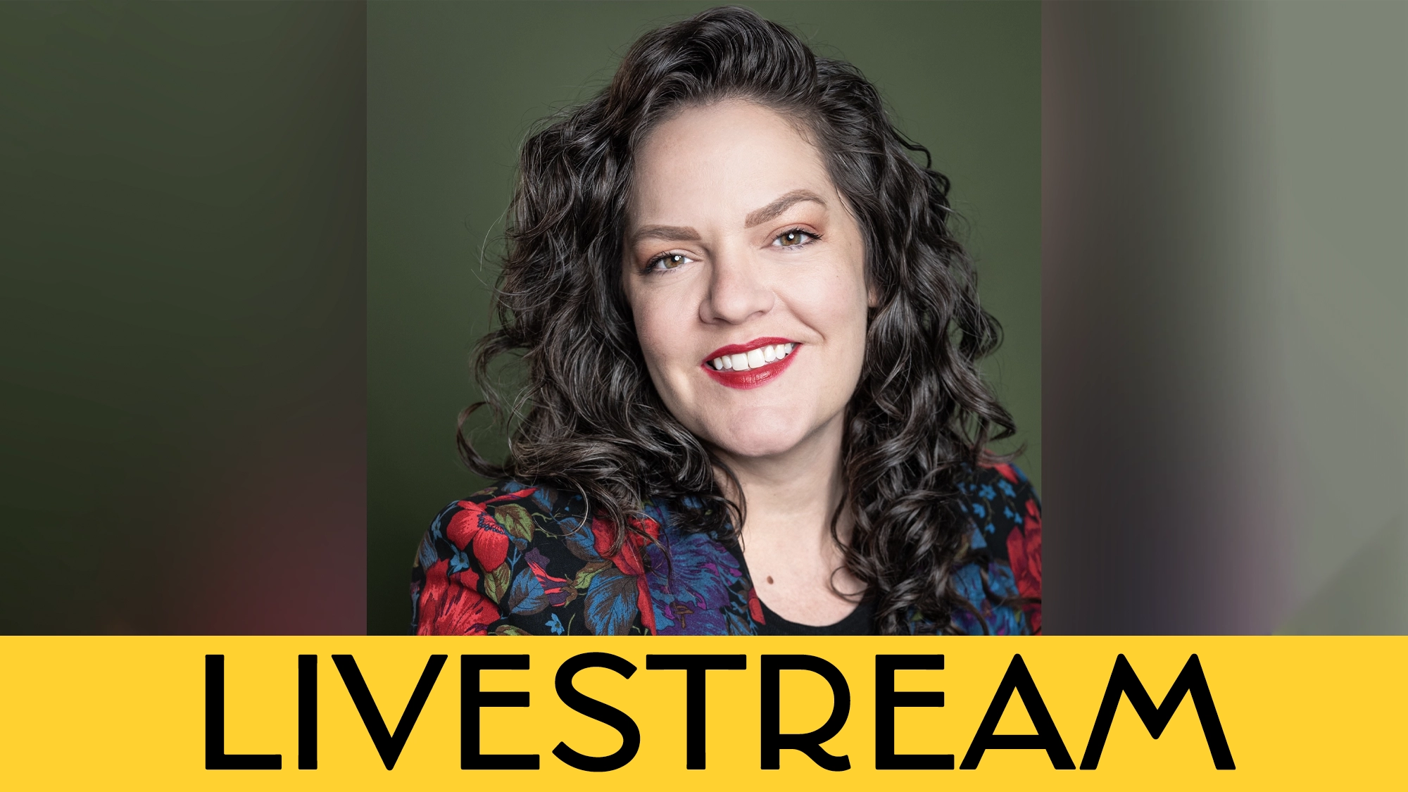 A woman with long curly brown hair and bright red lipstick smiles at the camera. She wears a dark, floral jacket. The background is olive green, with 