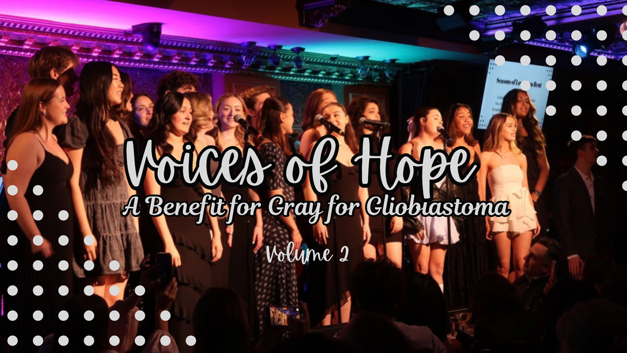 A diverse group of young performers stand on stage singing under purple and orange lighting. Large white text reads “Voices of Hope: A Benefit for Gray Glioblastoma Volume 2.” White dotted patterns border the photo.