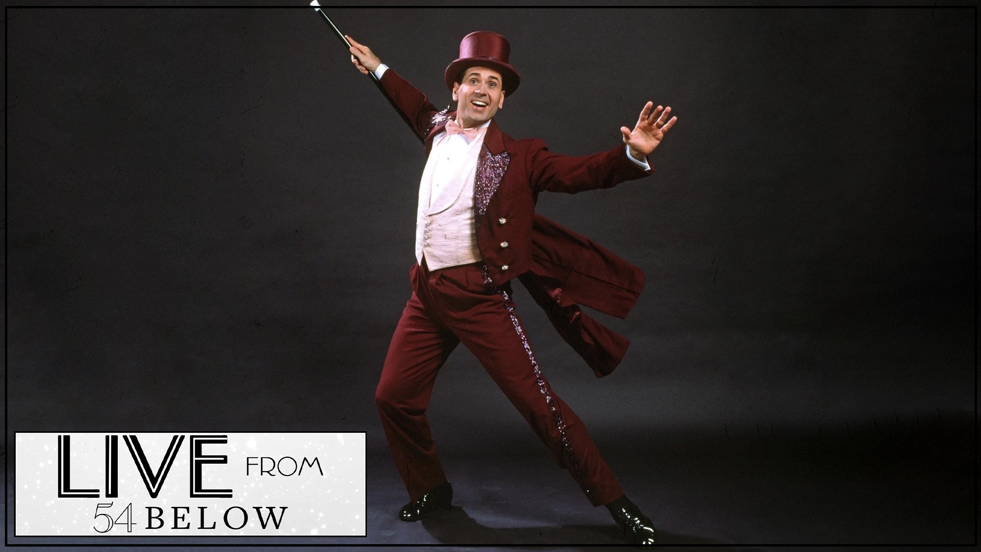 LIVE Lee Roy Reams A person in a maroon tailcoat, vest, pants, and top hat poses joyfully with one arm outstretched, holding a white-tipped cane. The background is plain dark. In the lower left, a “Live from 54 Below” logo hints at a 42nd Street livestream event.