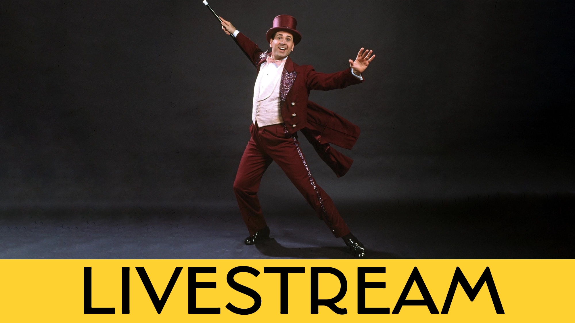 A performer in a burgundy tuxedo, top hat, and bow tie stands on one leg, arm raised with a cane, smiling joyfully on a dark stage—evoking the spirit of 42nd Street. A yellow “LIVESTREAM” banner appears boldly at the bottom.