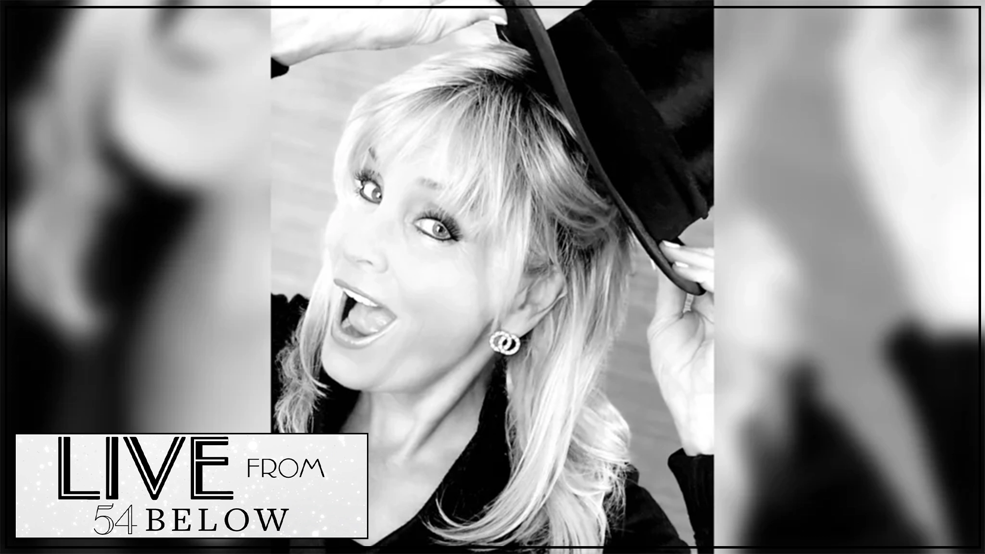 A blonde woman with bangs smiles widely and lifts a black hat with one hand. She wears round earrings and a dark top. The image is in black and white, and the 