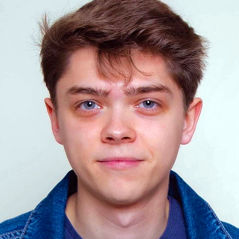 Austin Nedrow, a young man with fair skin, short brown hair, and blue eyes, looks directly at the camera with a neutral expression. He wears a dark shirt and a blue denim jacket, posed against a plain light background.