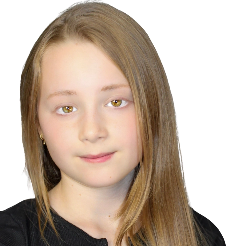 Saraphina Dinin, a young girl with straight, light brown hair and fair skin, looks at the camera with a gentle expression. She is wearing a black top and small gold earrings against a plain white background.