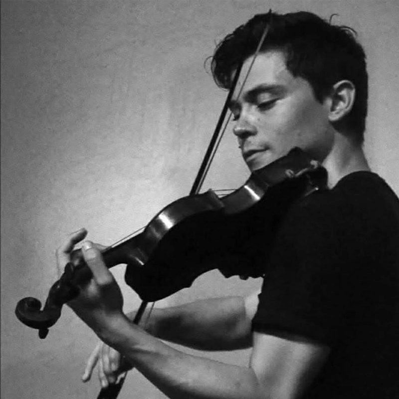 A young man with short, dark hair plays a violin. He wears a dark T-shirt and is focused on his performance. His left hand presses the strings while his right moves the bow. The image features Edmund Bagnell in black and white against a plain background.