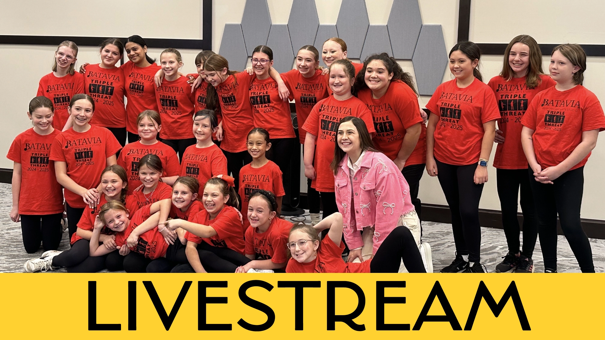 LIVE Triple Threats Calendar A group of 26 smiling girls and one adult, all wearing matching bright red