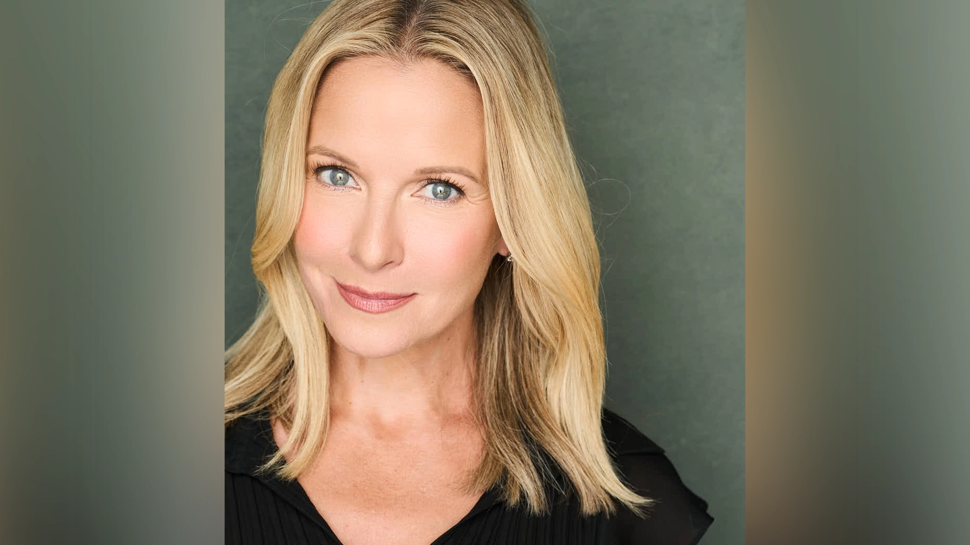 Meredith Patterson - Show Image A woman with straight blonde hair and blue eyes gazes directly at the camera, smiling softly. She wears a black top against a muted green background—an image reminiscent of Meredith Patterson in Confessions of an Actress, set in vibrant New York.