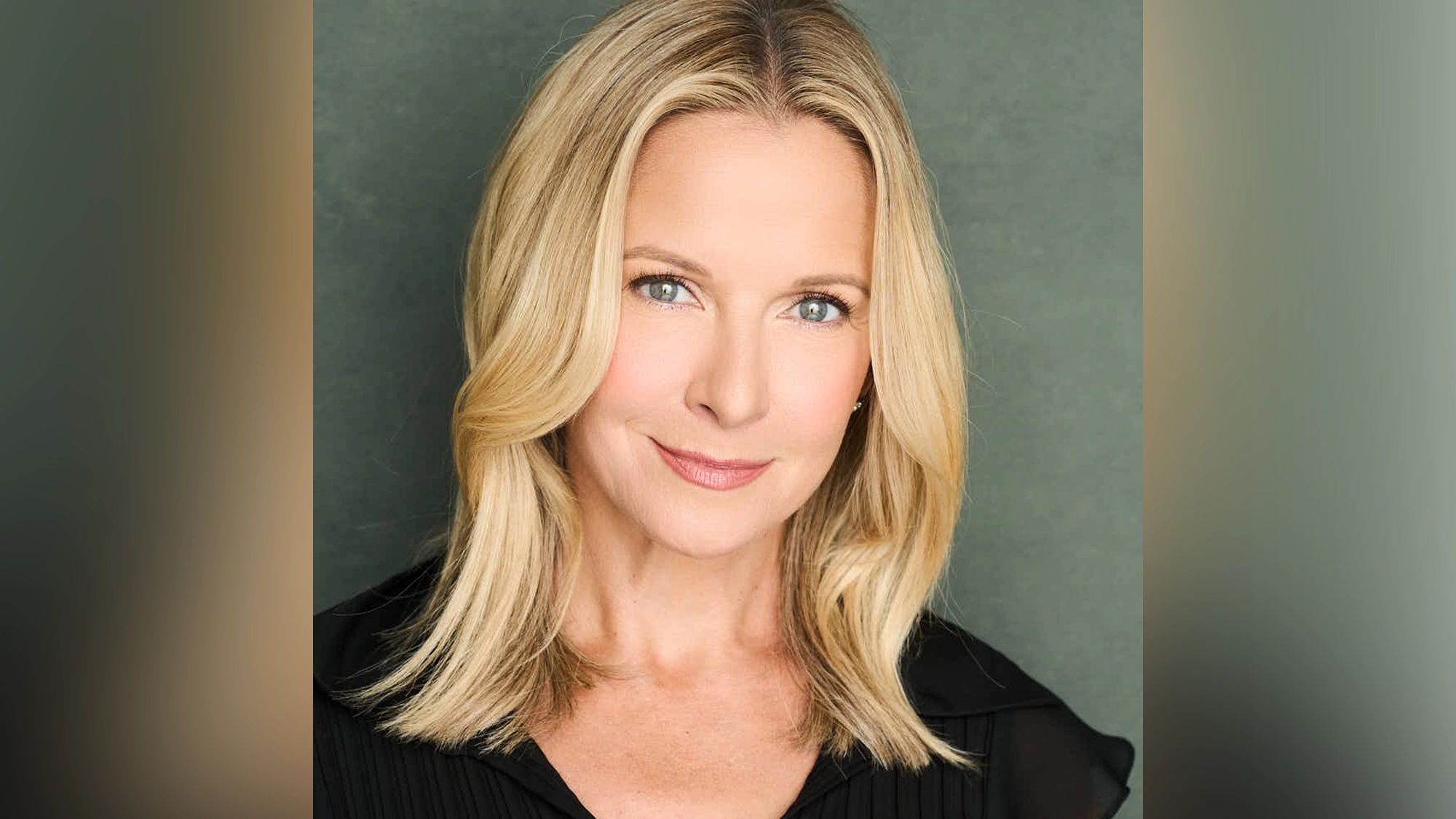 Meredith Patterson - Show Image A woman with straight blonde hair, parted in the middle, is smiling softly. She has light skin and blue eyes, and wears a black top. The bright lighting highlights her face—she could be Meredith Patterson in New York, ready for Confessions of an Actress.