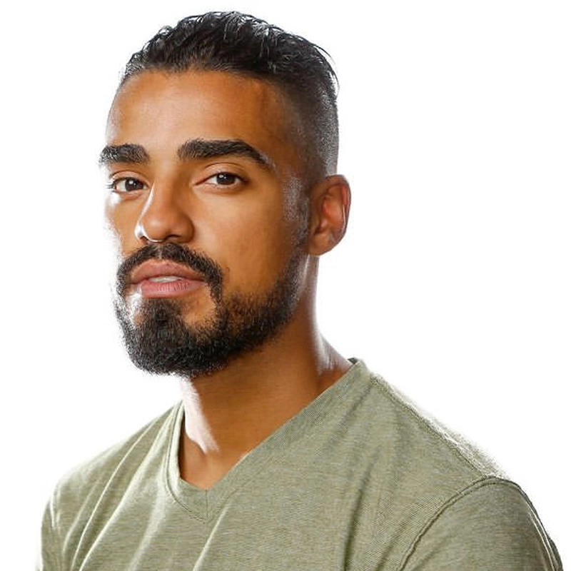 Michael Mendez, a man with short, slicked-back dark hair and a trimmed beard, wears a light olive-green shirt. He faces slightly left, looking at the camera with a neutral expression. The background is plain white with bright, even lighting.