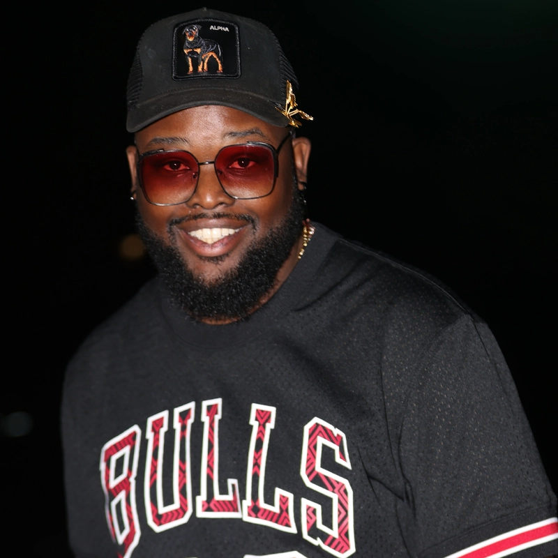 A smiling man with a beard wears a black 