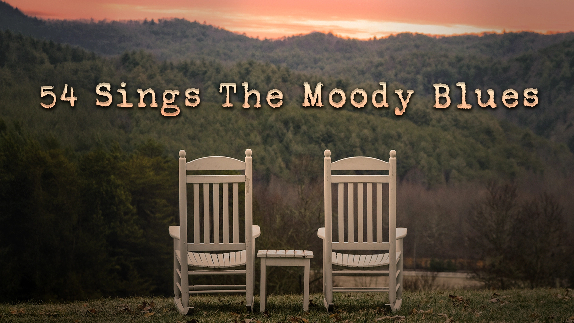 54 Sings The Moody Blues - Site Image Two white rocking chairs sit side by side on grass, facing a scenic view of tree-covered hills at sunset. Between them is a small table. The sky glows orange and pink. Large text above reads: “54 Sings The Moody Blues.”.