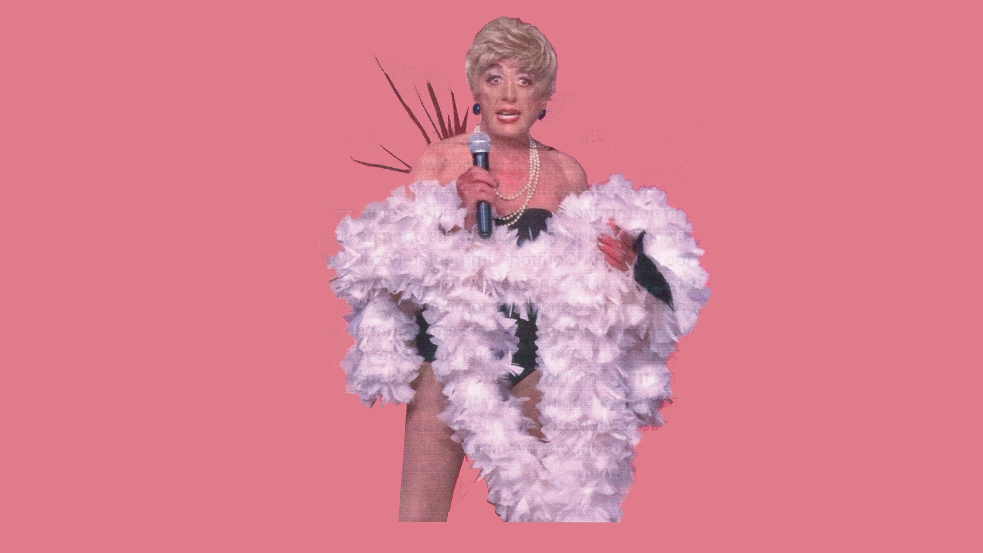 A performer stands against a pink background, wearing a short blond wig, pearl necklace, black outfit, and a large white feather boa, holding a microphone and appearing to sing or speak energetically.