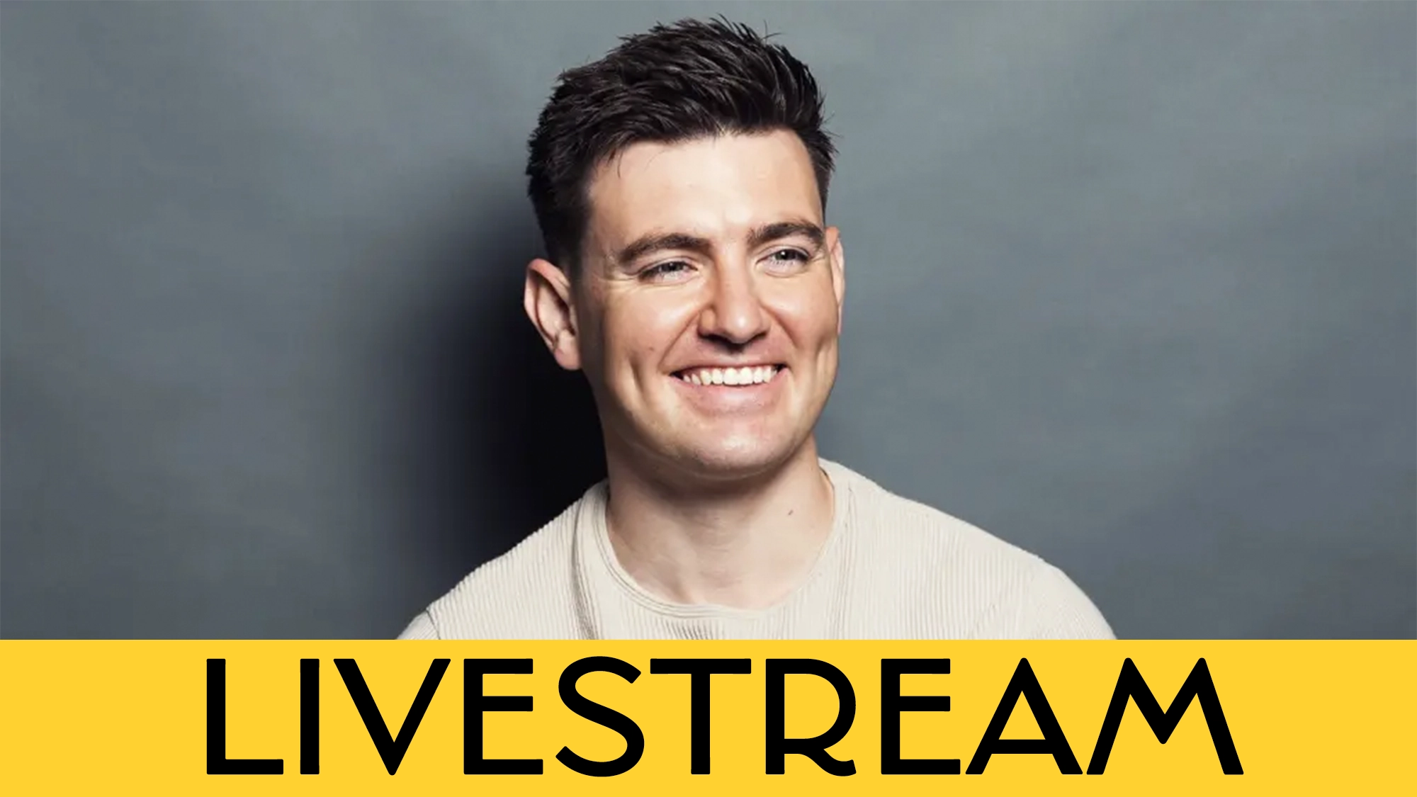 Emmet Cahill calendar image A smiling man with short dark hair and a light beige sweater sits in front of a plain gray background. A bold yellow banner at the bottom displays the word