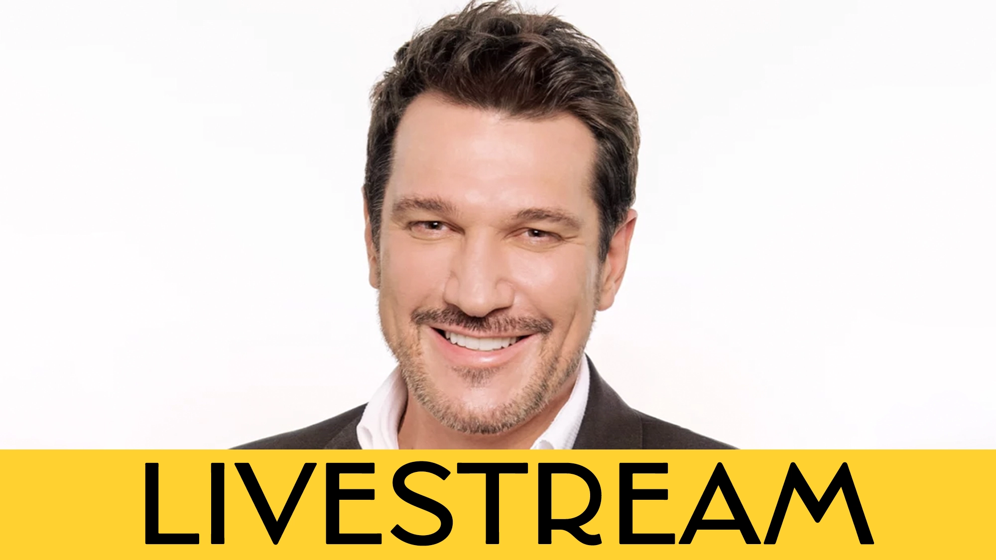 Paulo Szot calendar image A smiling man with short dark hair and facial stubble in a dark suit against a white background. Across the bottom, a bold yellow banner displays the word “LIVESTREAM” in large black letters.