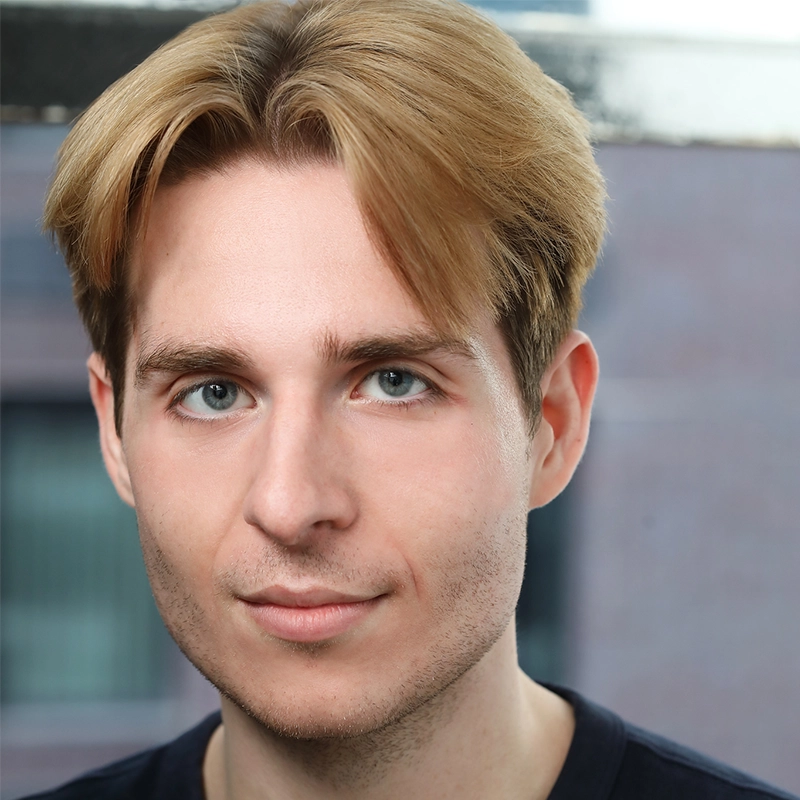 Headshot of a man with light brown hair parted in the middle and light-colored eyes. He has a neutral expression and light stubble on his face.
