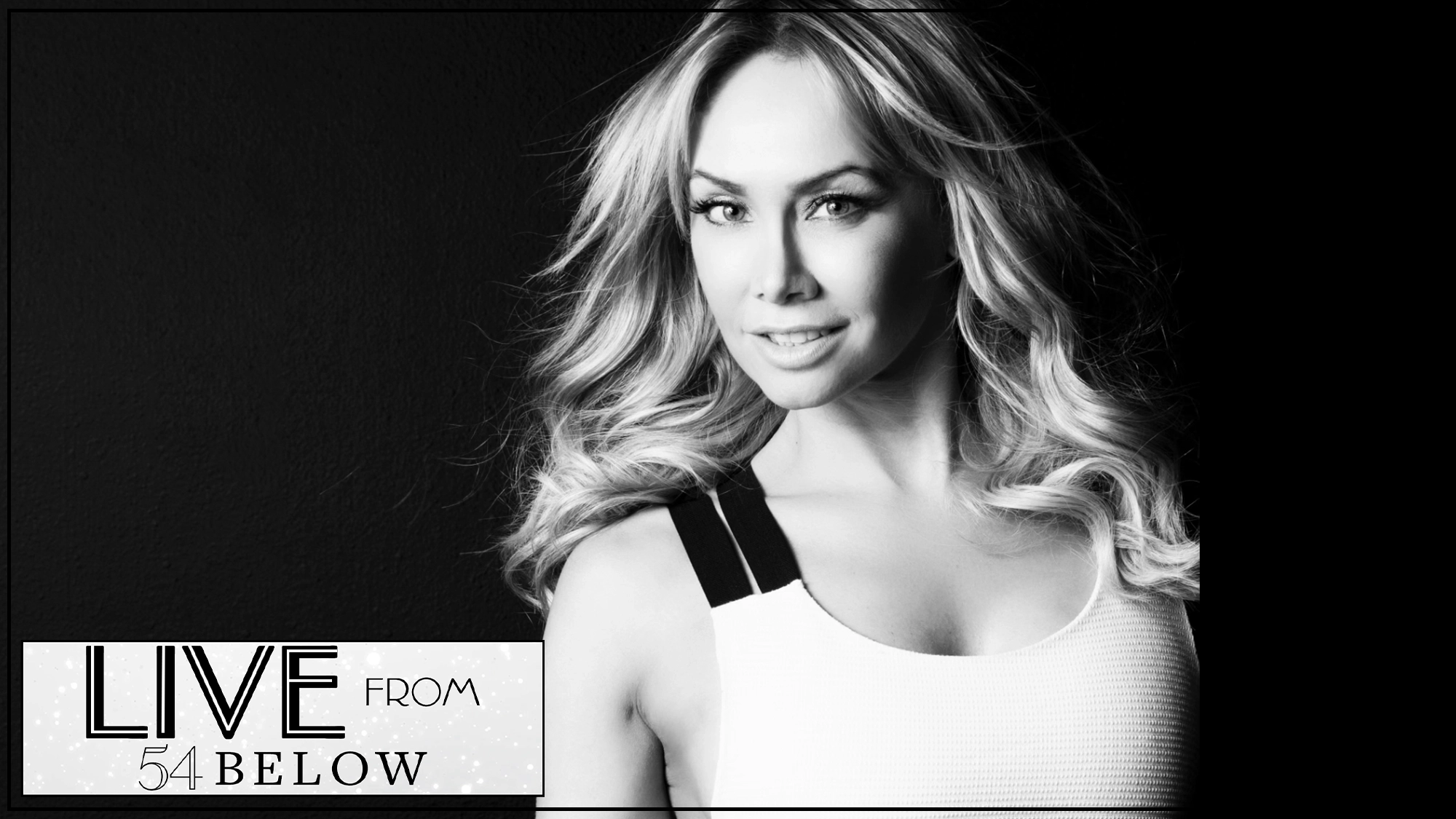Black-and-white photo of a woman with wavy hair, smiling slightly at the camera. She wears a white tank top with dark straps. In the lower left corner, a text box reads “LIVE FROM 54 BELOW” in art deco style, highlighting this special Livestream event. The background is dark and plain, evoking a classic atmosphere reminiscent of Kym Johnson performing “What I Did For Love.”.