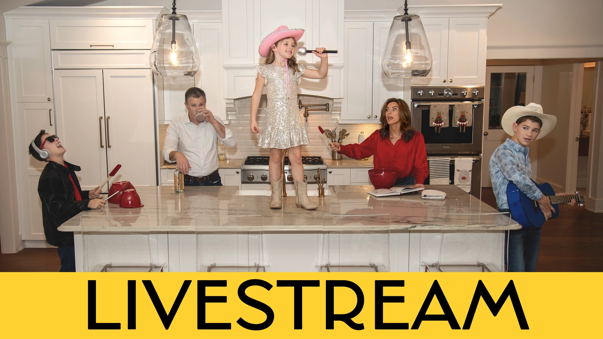 A family in a bright kitchen mimic a band: a girl in a sparkly dress and pink cowboy hat sings on the island, her mom in red—Jenny Powers—holds a whisk as a mic, dad Matt Cavenaugh snacks, a boy in cowboy gear plays guitar, and another child wears headphones and drums. Bold “LIVESTREAM” text below celebrates this joyful scene from the Cavenaugh Powers Family.
